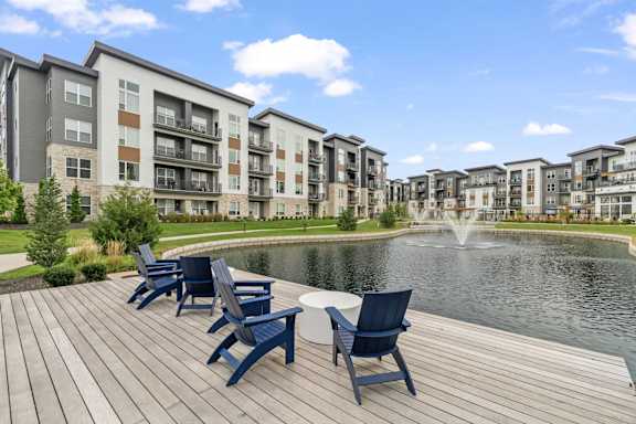 an outdoor patio with blue chairs and a pond with a fountain