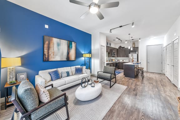 a living room with a blue accent wall and a kitchen