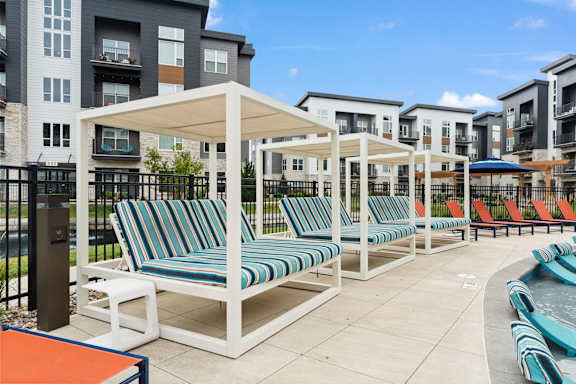 an outdoor pool with lounge chairs and umbrellas at the choices at trinity
