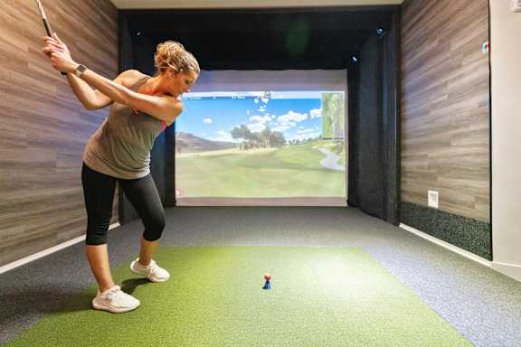 a woman is swinging a golf club at a mini golf ball