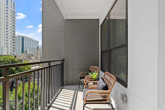 A balcony with two chairs and a table with a plant on it.