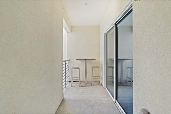 a hallway with glass doors and a table on a balcony