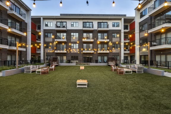 an outdoor lounge area with lounge chairs and a fire pit in the middle of an apartment complex