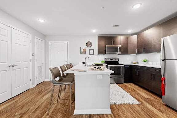 a kitchen with a white island and a stainless steel refrigerator