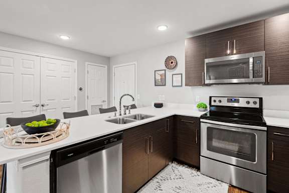 a modern kitchen with stainless steel appliances and white countertops
