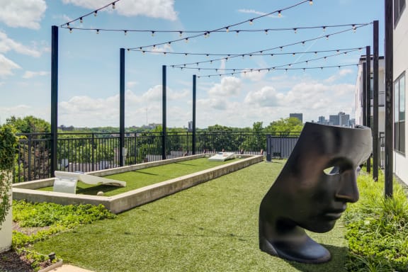 a rooftop garden with a sculpture of a head and a city skyline in the background