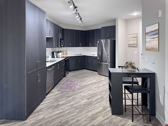 A kitchen with dark wood cabinets and a black island.