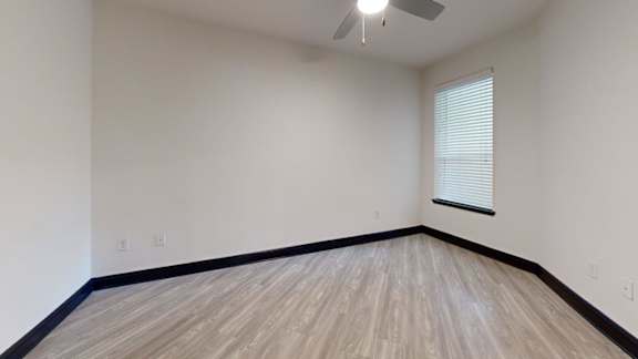 A room with wooden flooring and a ceiling fan.