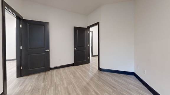 A room with a black door and a wooden floor.