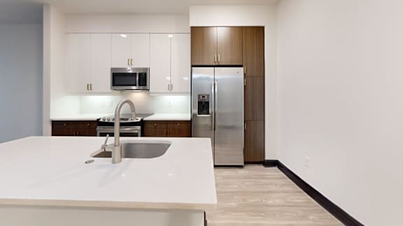 A modern kitchen with a white countertop and stainless steel appliances.