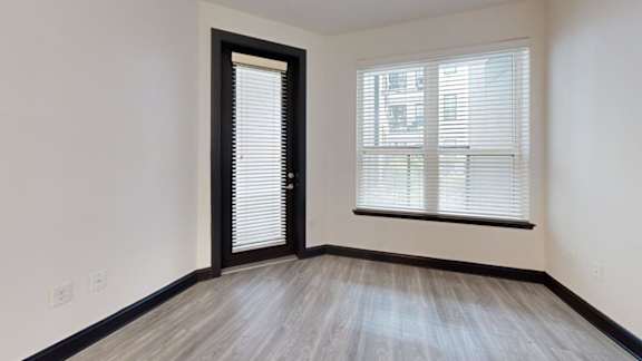 A room with a wooden floor and a window with blinds.