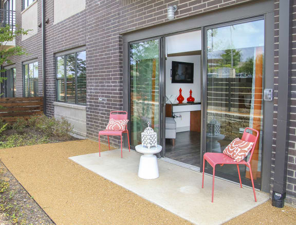 a patio with two chairs and a toilet outside of a brick house