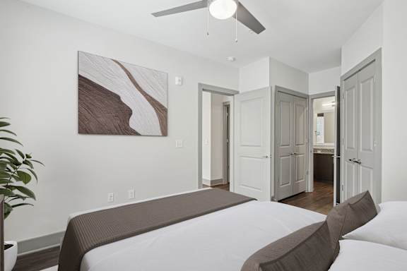 A bedroom with a bed, a ceiling fan, and a painting on the wall.