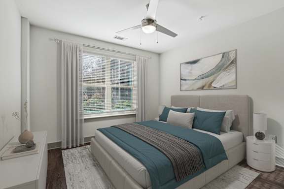 A bedroom with a bed, a ceiling fan, and a window with curtains.