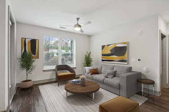 A living room with a grey couch, a brown coffee table, and a painting on the wall.