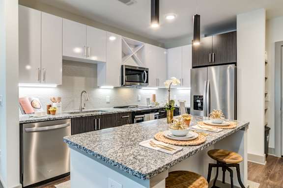 A modern kitchen with a granite countertop and stainless steel appliances.