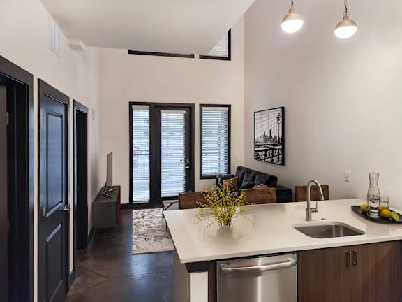 A kitchen with a white counter top and a stainless steel dishwasher.