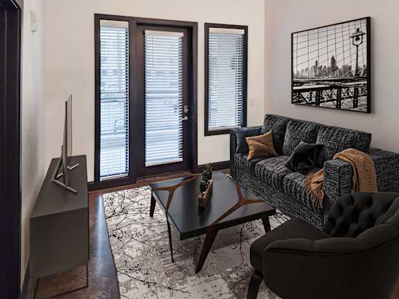 A living room with a grey couch, a black chair, a wooden table, and a television.