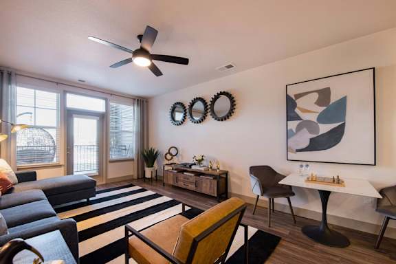 A living room with a striped rug and a ceiling fan.
