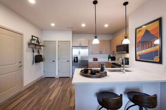 A kitchen with a white counter and brown chairs.