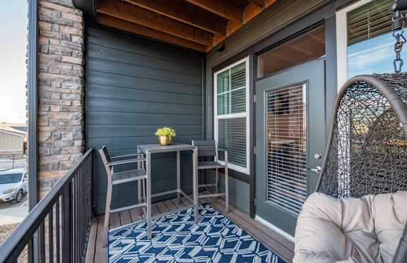 A small table with a vase of flowers on it sits on a porch.