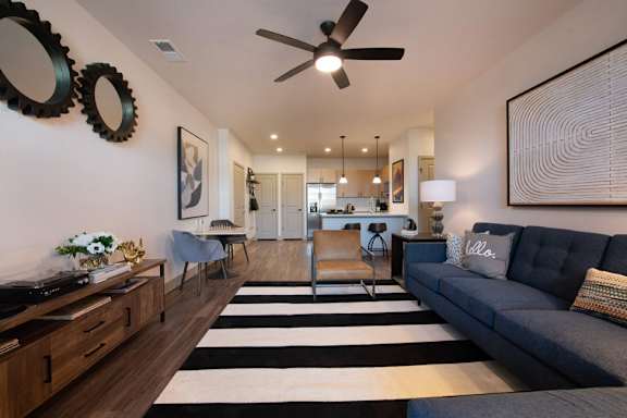 A living room with a striped rug and a grey couch.