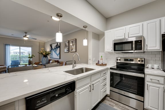 Kitchen with white cabinets and stainless steel appliances at Highland Luxury Living, Texas, 75067