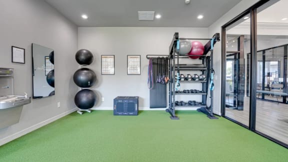 Fitness center with a treadmill and weights at Highland Luxury Living Apartments in Lewisville, TX