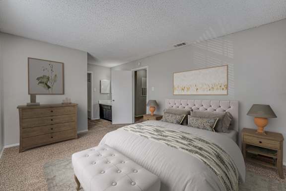 A bedroom with a large bed, a dresser, and a nightstand with a lamp.