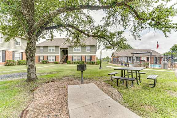 Outdoor picnic area with grill and pool access at Arbors Of Corsicana Apartments, Corsicana, Texas
