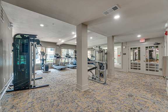 A gym with a variety of equipment including treadmills, weights, and exercise machines.