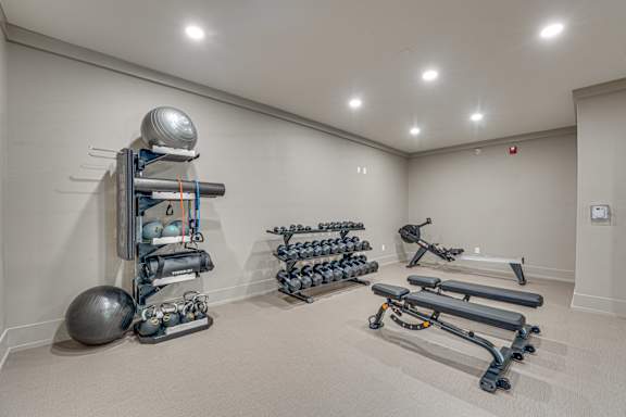 A room with a variety of exercise equipment including a weight rack, exercise balls, and resistance bands.