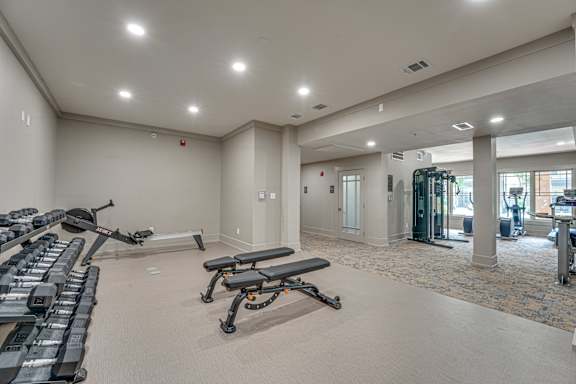 A spacious gym with treadmills, elliptical machines, and weight benches.
