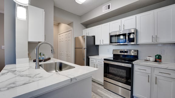 Modern kitchen with white cabinets and stainless appliances at Carmel Creekside Apartments, Fort Worth, Texas