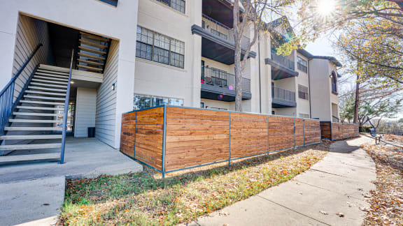 Exterior staircase and wooden perimeter fencing at Carmel Creekside Apartments, Texas, 76137
