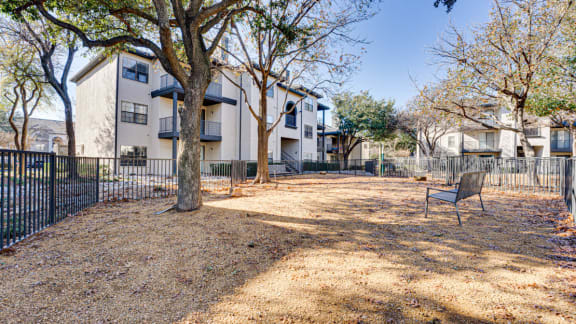 Fenced courtyard area with mature trees and bench at Carmel Creekside Apartments, Fort Worth, TX 76137