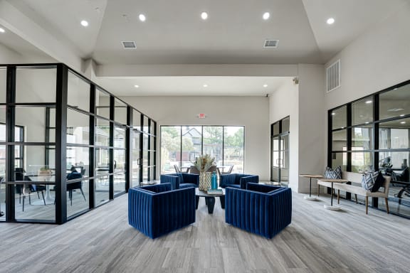 Clubhouse lobby with blue seating and black framed glass walls at Carmel Creekside Apartments, Fort Worth, TX