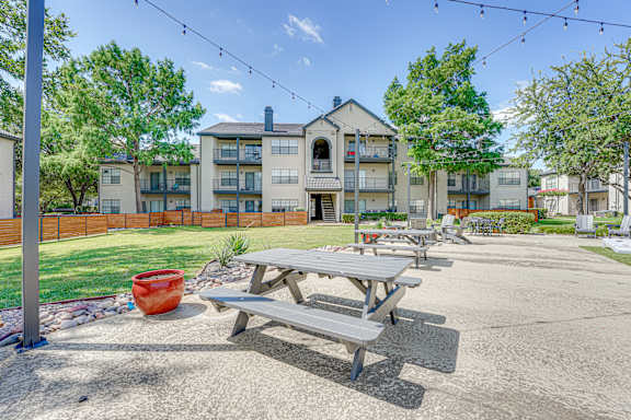 Outdoor picnic area with tables and string lights at Carmel Creekside Apartments, Texas