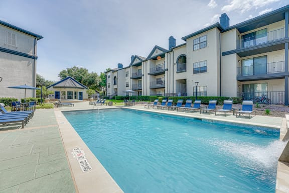 Swimming pool with lounge chairs and balcony views at Carmel Creekside Apartments, Fort Worth, TX