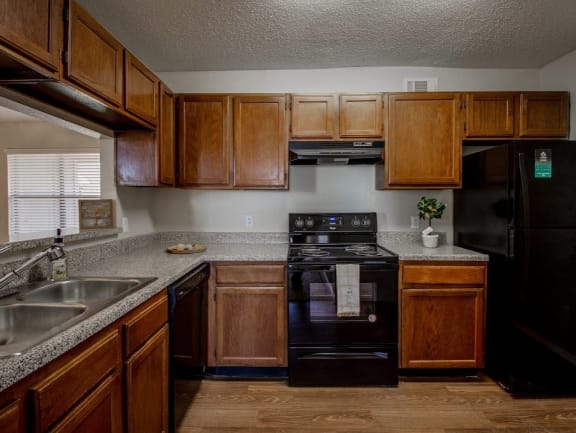Kitchen with black appliances and speckled countertops at Towne Centre Village Apartments, Mesquite, Texas