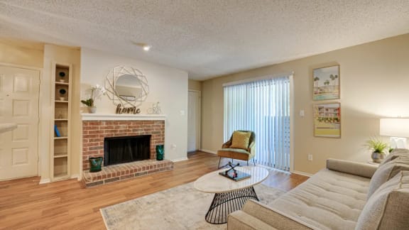 Living room with a fireplace and a couch at  Indian Creek Apartments in Carrollton, TX