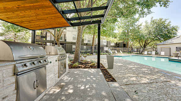 A stainless steel BBQ grill is on a patio next to a pool at Knox Allen Station, Allen, 7\5002