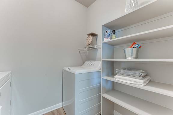 A white bathroom with a toilet and towel shelf.