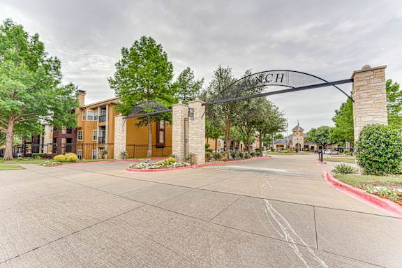 Property entrance archway with stone columns and landscaping at Limestone Ranch Apartments, Lewisville, Texas