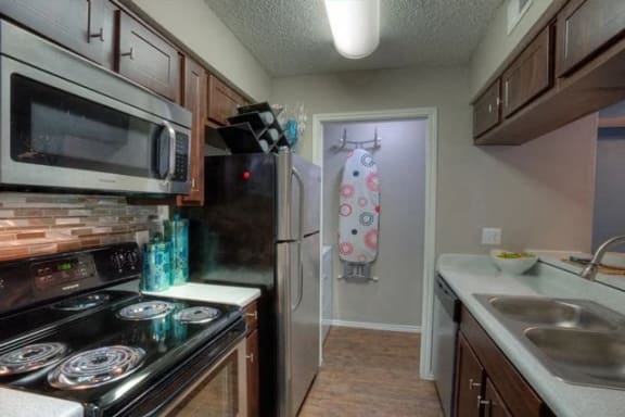 Kitchen with a stove top oven next to a refrigerator at The Manhattan Apartments, Dallas