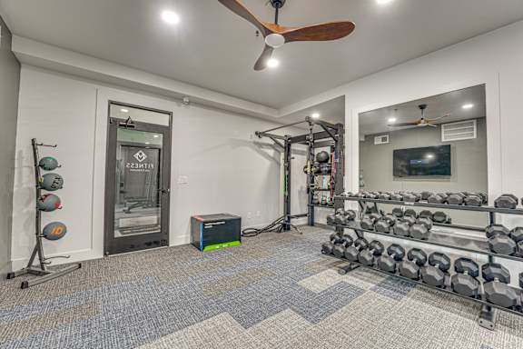 Fitness center with dumbbell racks and workout equipment at The Montrose Apartments, Dallas, TX 75204