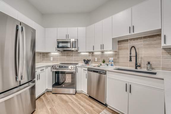A modern kitchen with stainless steel appliances and white cabinets.