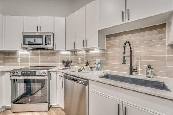 A modern kitchen with a stainless steel oven and white cabinets.