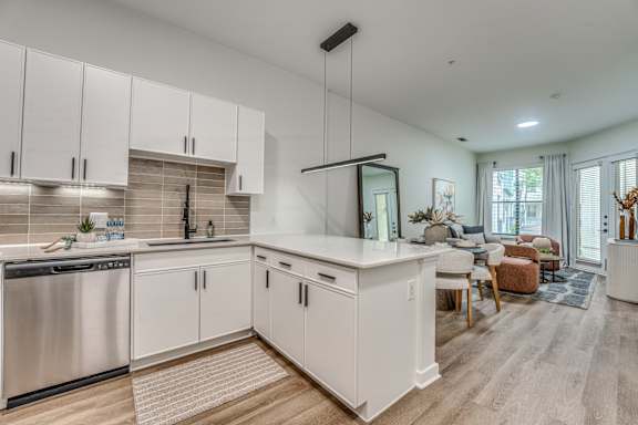 A modern kitchen with white cabinets and a wooden floor.