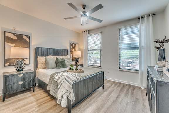 Spacious bedroom with two windows and decorative furnishings at The Barton Apartments, Texas